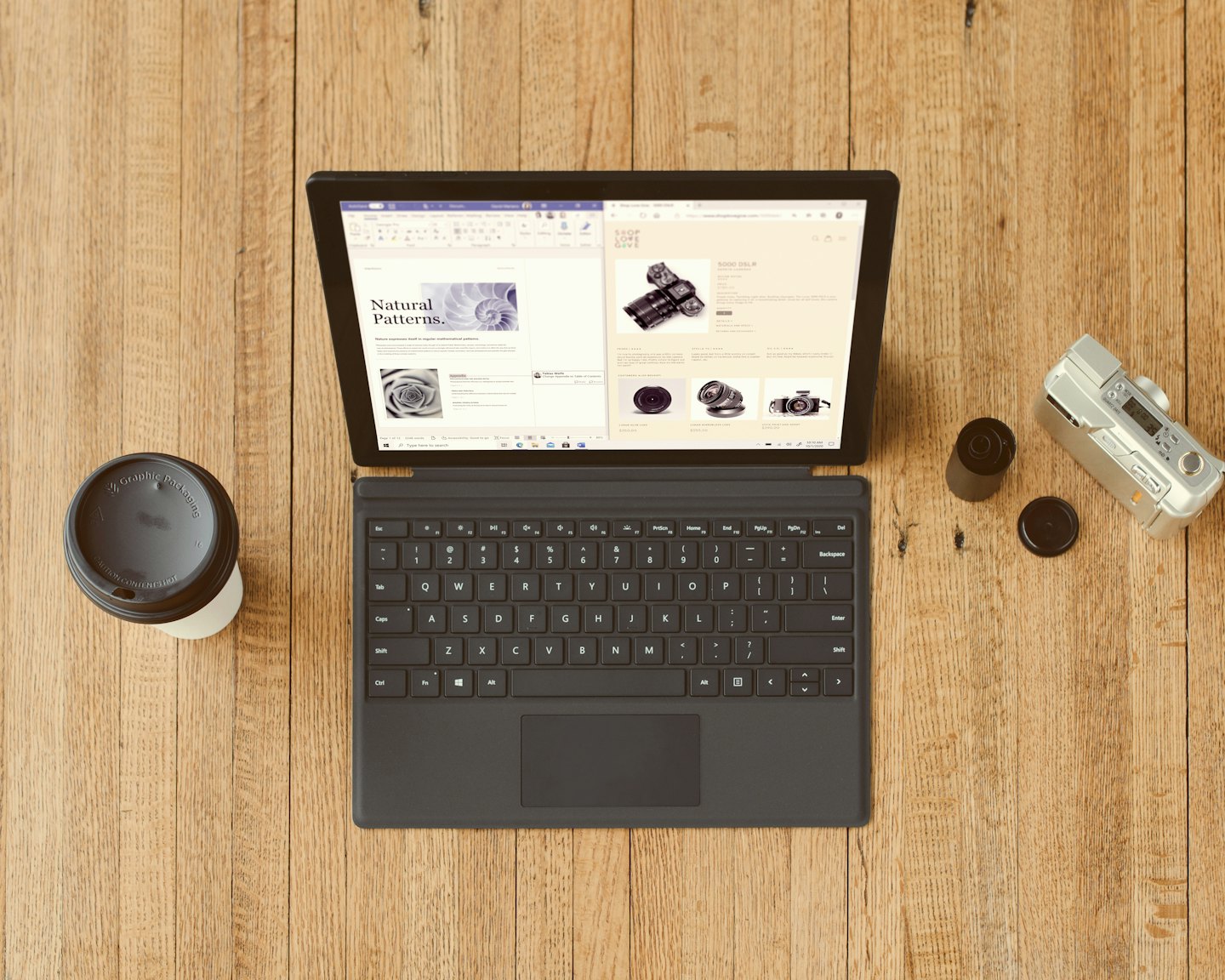 Laptop, coffee cup, and camera arranged on a wooden desk.